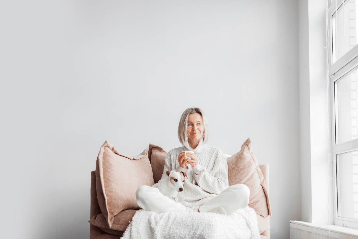 woman sitting with dog drinking a warm drinking looking refreshed